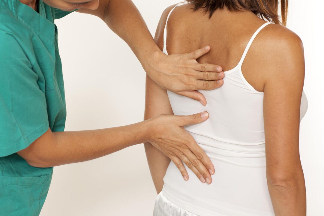 A doctor examines the back for pain in the shoulder blades